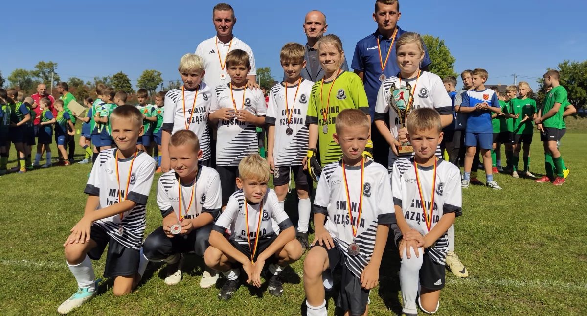Na zdjęciu zawodnicy zwycięskiej drużyny LKS-u Czarnych Rząśnia w roczniku 2015 wraz z trenerem Tomaszem Filipiakiem, wójtem gminy Strzelce Wielkie Damianem Ciemciochem oraz Robertem Krzypkowskim z GLKS-u Strzelce Wielkie, który to zespół był gospodarzem turnieju/fot. Łukasz Płuciennik ( wszystkie )