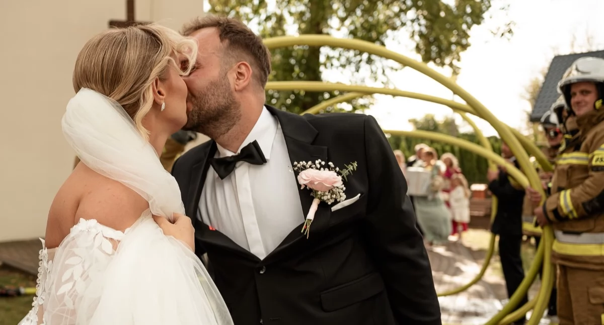 Na zdjęciu ślub w strażackiej oprawie. Małżonkowie Wiktoria Kupis i druh Damian Smugowski /  fot.: Moment Fotografia i Film
